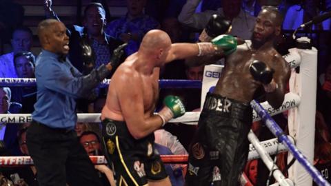 Tyson Fury punches Deontay Wilder as he referee jumps in to stop the fight