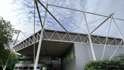 The outside of Swindon's Link Centre - a small stadium building with a white tubular exoskeleton.