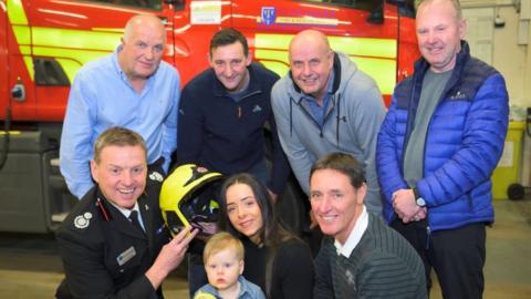 Jade Broderick and baby Blake with firefighters who saved her life on her first birthday, from left, back row, John Mather, Andy Hinde, Dave Morris and Damon Leonard; front row, Gus O’Rourke and Martin Dowle