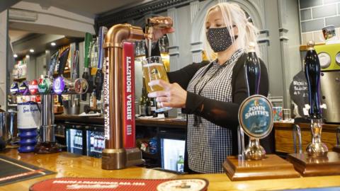 A woman serving a pint in a pub in Haworth, West Yorkshire