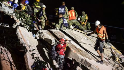 Rescuers, firefighters, police, military personnel and volunteers remove rubble and debris from a flattened building in search of survivors after a powerful earthquake in Mexico City, 19 September 2017