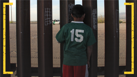 Boy looks through metal border fence in Ciudad Juarez