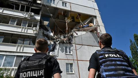 Officials inspect damage to a building in Kharkiv