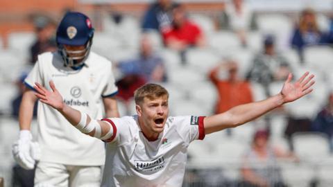 Mitch Stanley on his haunches appealing for a wicket for Lancashire