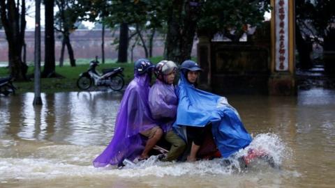 People ride a motorcycle along a flooded road after typhoon Damrey hits Vietnam (04 November 2017)