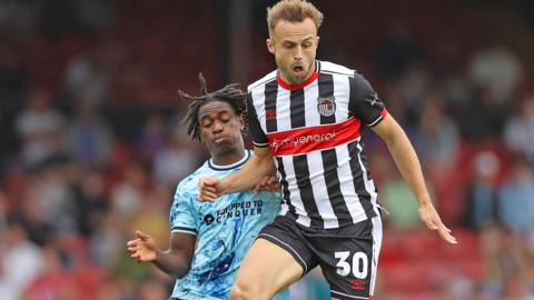 Habeeb Ogunneye of Newport County challenges Grimsby's Charles Vernam for the ball