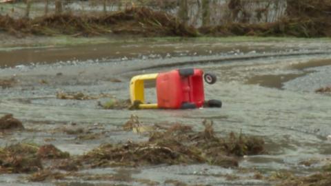 A red and yellow child's car on it's side surrounded by water