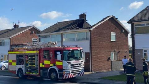 Fire engine in front of house with damaged rood