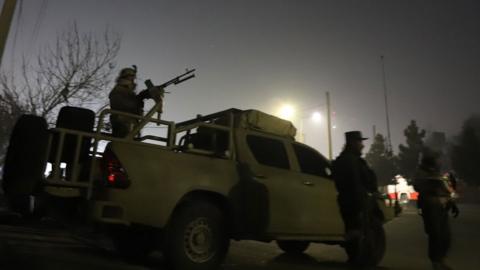 Security forces, including one soldier operating a vehicle-mounted machine gun, take up position outside the hotel