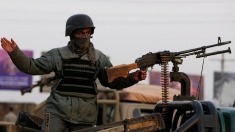 An Afghan policeman keeps watch at a back of truck at the site of an attack in Kabul