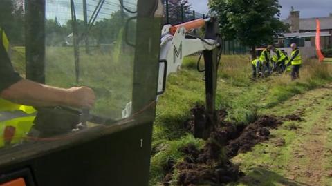 Volunteers and a digger help lay the first track