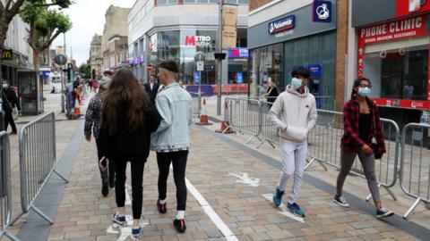 Members of the public walk through the city centre which has been marked out with social distancing markings on July 04, 2020 in Wolverhampton, England