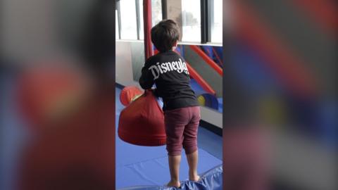A child standing at a soft-play area, holding a foam swing