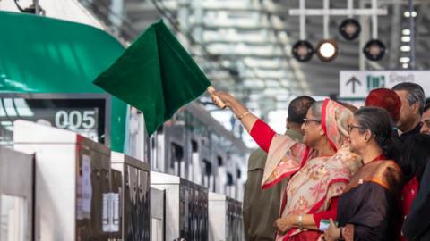 Bangladeshi Prime Minister Sheikh Hasina holds a green flag at the opening of the metro rail