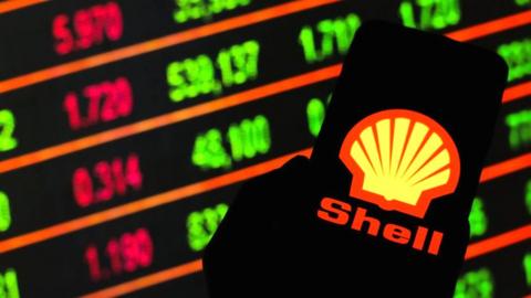 Shell logo on smartphone against stock market screen