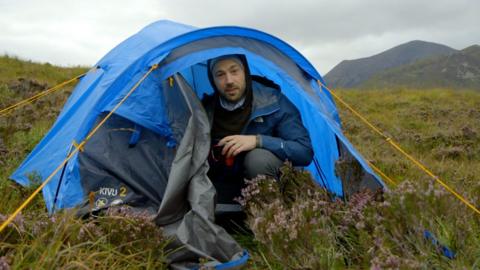 Mike Corey sits in a blue tent on the Isle of Skye