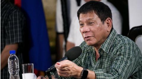 Rodrigo Duterte speaks during his press conference, seated at a microphone and wearing an open-necked check shirt, on 31 May 2016.