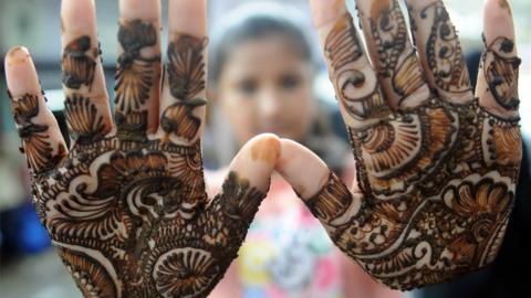 An Indian Muslim girl displays her henna decorated hands at a roadside stall ahead of the Muslim festivities of Eid al-Fitr, in Mumbai on July 28, 2014