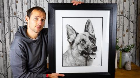 Artist Stuart Scott holding one of his pet portraits