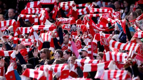 Arsenal fans holding scarves