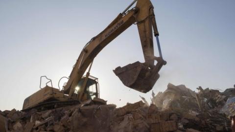 A bulldozer clears debris from buildings demolished by authorities in a migrant housing area on the outskirts of Beijing.