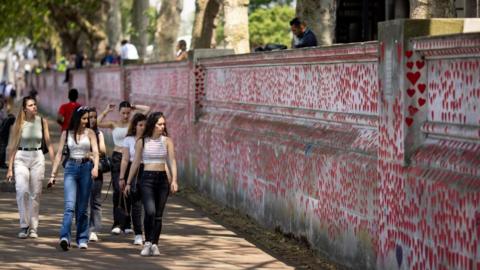 People walking next to the National Covid Memorial Wall in London