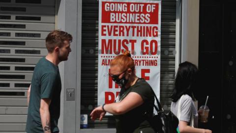 People walking past a shop that is closing down