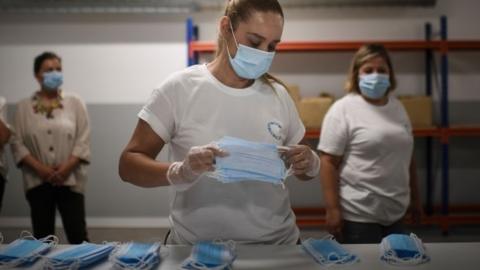 worker selects masks during the production of disposable face masks at a mask factory in Cascais, in the outskirts of Lisbon on June 5, 2020.