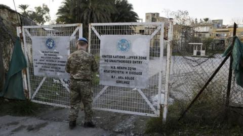 A UN soldier closes a gate leading to the inside of the UN buffer zone in Cyprus