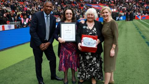 Grandchildren of Jack Leslie accepting honorary cap from FA Chair Debbie Hewitt MBE and former England international Viv Anderson