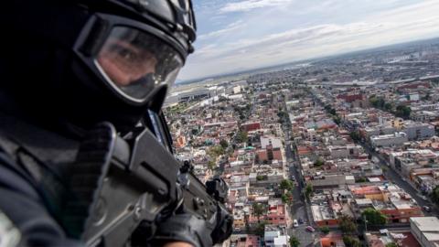 A policeman is seen on board a helicopter as it flies over Mexico City in 2018