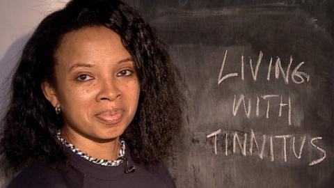 Natalie Lue stands in front of a blackboard reading "Living with tinnitus"