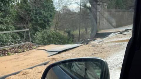 View from car window of collapsed road and bridge