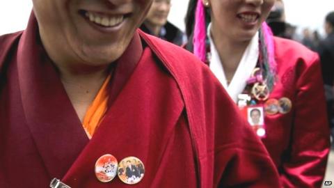 Delegates, wearing pins of images of Chinese President Xi Jinping and former leaders, arrive at the Great Hall of the People in Beijing on 3 March 2016