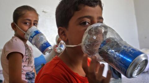 Children try improvised gas masks in their home in Syria's rebel-held northern Idlib province