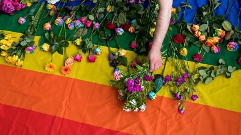 Man lays flowers on LGBT flag at demonstration at Russia's London embassy - 2017 photo