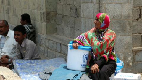 A Yemeni woman sits next to blankets and upholstery distributed by the UNHCR in the Yemeni city of al-Hudaydah