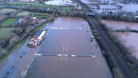 The flooded rugby pitch seen from above. Fields around the pitch are flooded too.