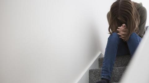 Teenage girl sitting on stairs with head down in despair