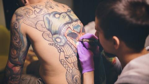 Tattooist working on a man's back