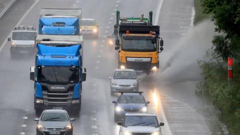 A lorry passes through a large puddle on the M20 in Ashford, Kent