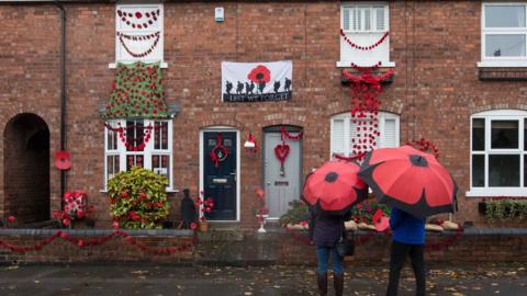 People look at a house in Station Road, Aldridge in Walsall which has transformed itself into Poppy Road as almost 100 houses have been decorated with 24,000 red poppies and silhouette statues of soldiers to honour local people who endured and lost their lives in the First World War.