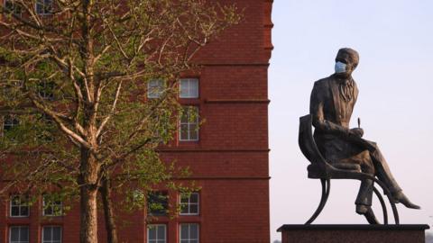 A coronavirus mask on a statue in Cardiff Bay