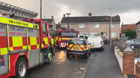 Fire engine and cars outside house with damaged roof