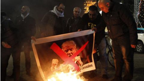 Palestinian protesters burn pictures of US President Donald Trump at the manger square in Bethlehem on December 5, 2017