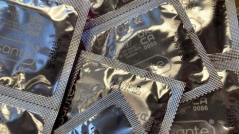 Condoms in silver packaging piled on top of each other.