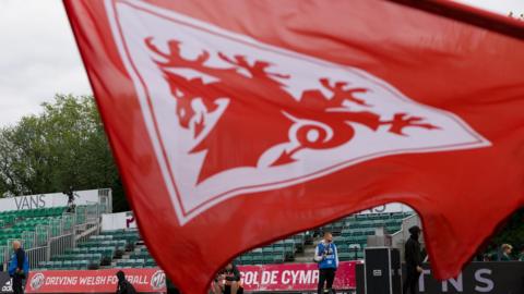 A Football Association of Wales red dragon flag flies at a football ground