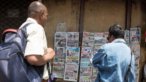 Madagascans read newspaper front pages in central Antananarivo