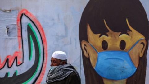 Palestinian man walking past mural in Gaza Strip.