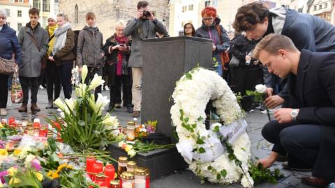 Young mourners place flowers at a makeshift memorial of flowers and candles on October 10, 2019